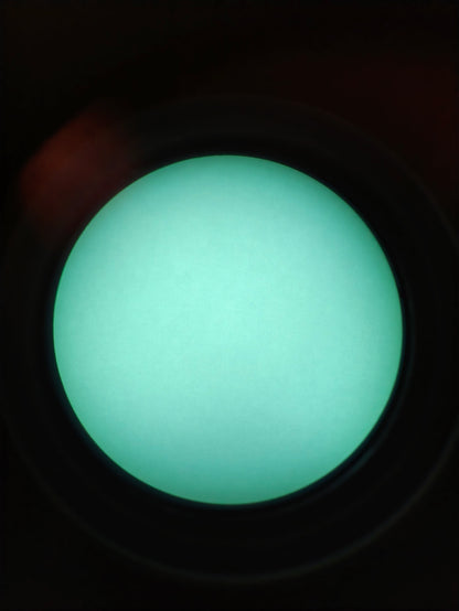 Through-tube photograph from a TC-X1 ATOM white-phosphor night vision binocular, view one; photographed colour and brightness may vary from direct viewing.