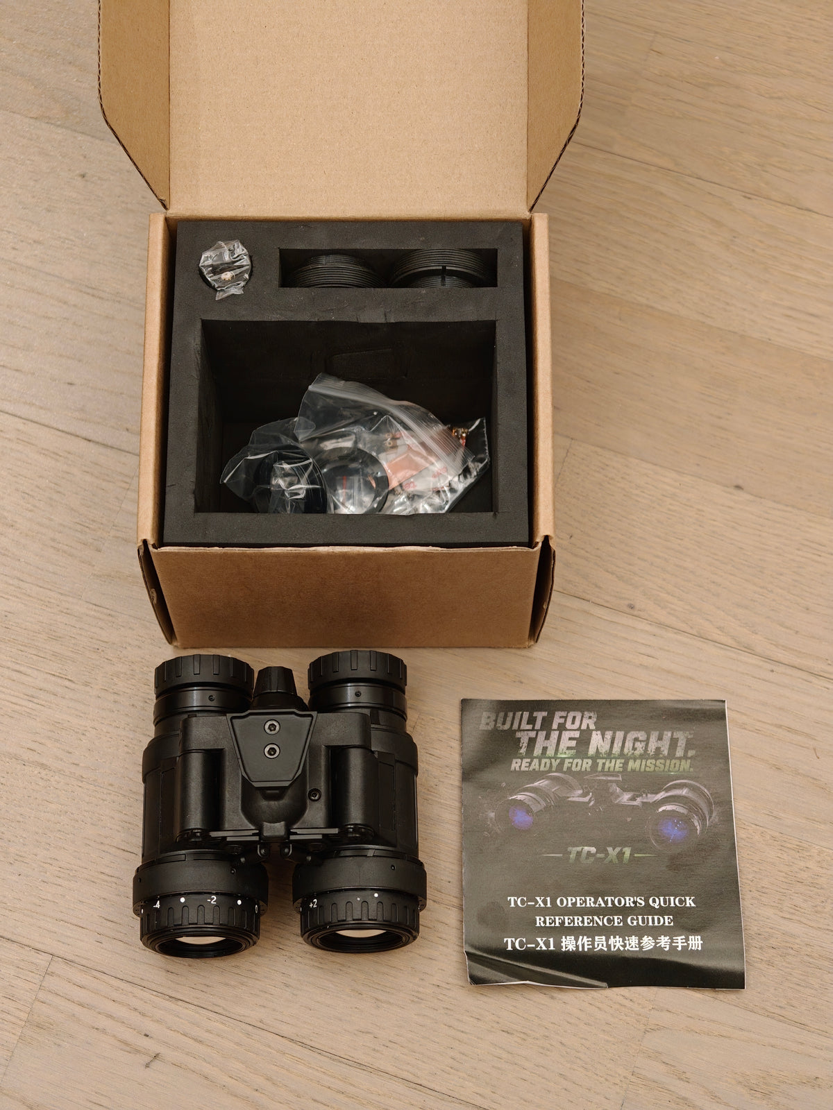 TC-X1 night vision binocular with opened packaging, accessories and quick reference guide